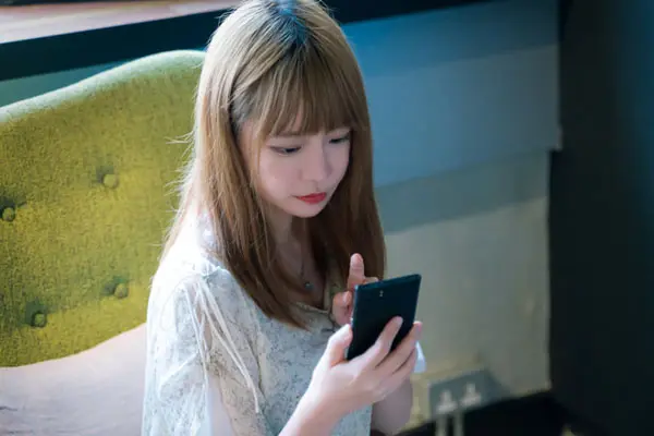スマホでAV事務所の評判を調べる女性